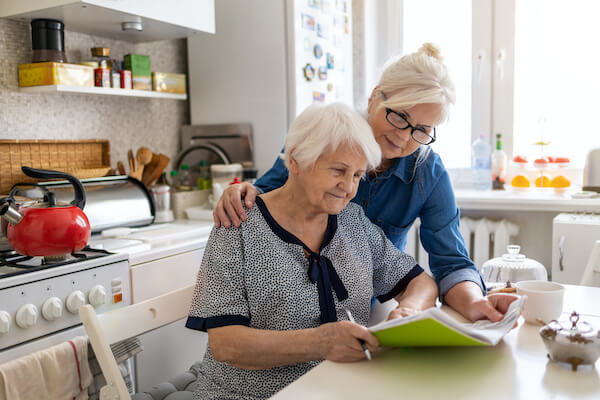 Mature woman helping elderly mother with paperwork.