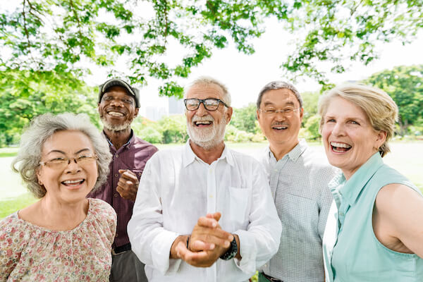 Group of senior retirement friends smiling in a group outside.
